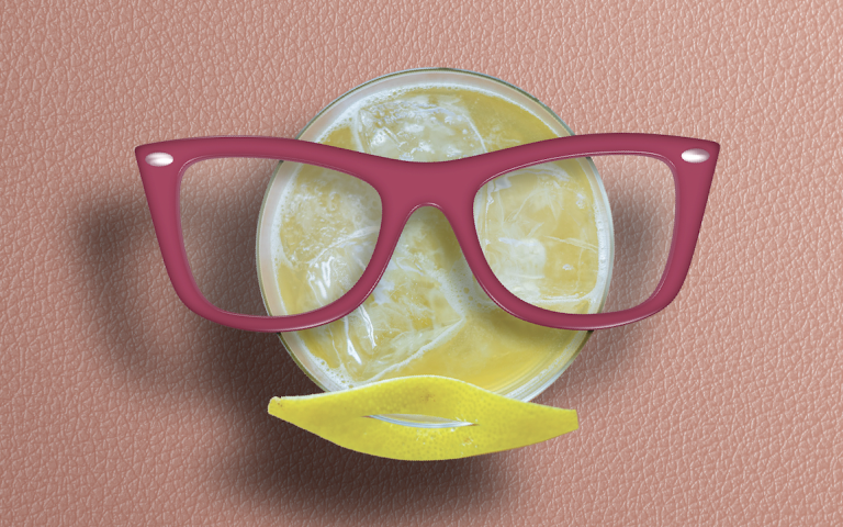 Cocktail with thick mid-century framed glasses and a lemon carcass as lips